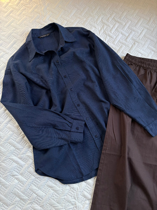 Navy shirt and brown pants on a textured white surface